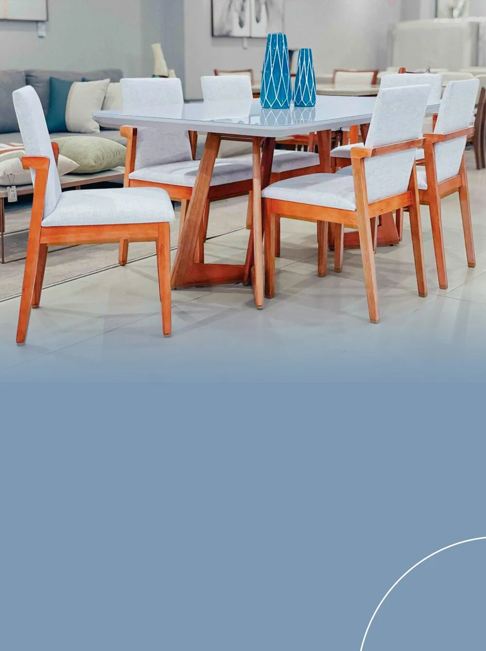 Conjunto de sala de jantar em madeira com mesa de tampo claro brilhante e seis cadeiras com assentos e encostos estofados em tom cinza claro.